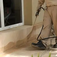 General pest control technician spraying exterior perimeter around a home in {city}, {state}
